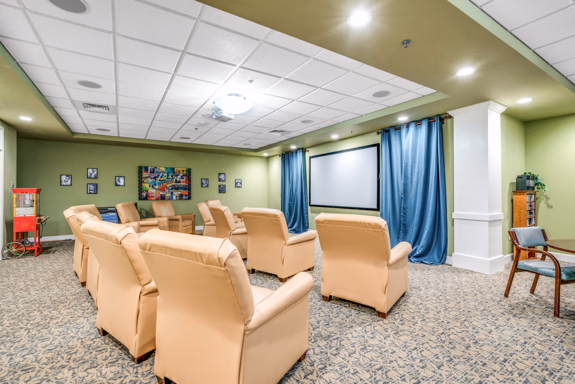 A cozy media room with beige recliner chairs arranged facing a large projection screen framed by blue curtains.