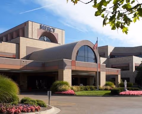 Sunny exterior view of Mount Vernon Assisted Living building with curved entrance canopy and landscaping.