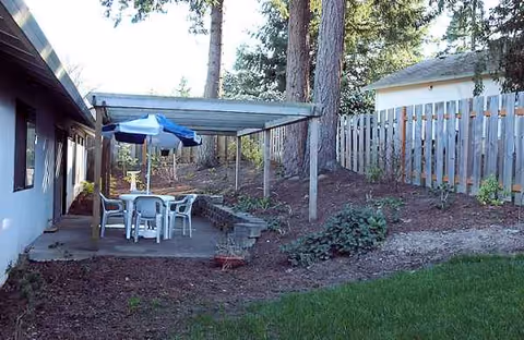 Outdoor patio area with a table, chairs, and umbrellas next to a building.