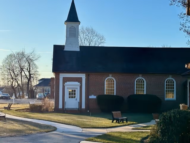 Brick church-like building with a white door, steeple, and arched windows