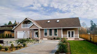 Front view of a single-story senior living facility with driveway, lawn, and landscaping.