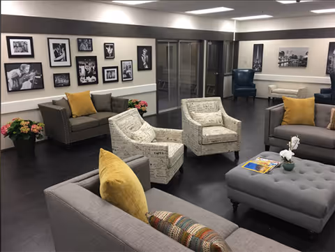 Modern living room lobby with gray sofas, chairs, pillows, and a wall photo gallery.