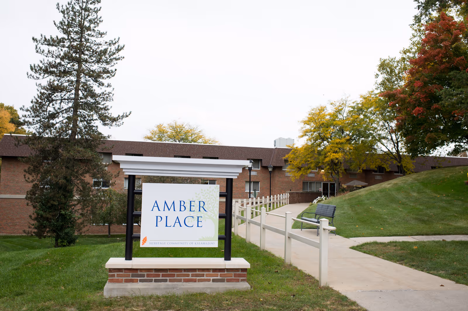 Sign for Amber Place at Heritage Community of Kalamazoo in front of a brick building and landscaped area.