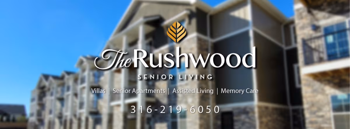 Exterior view of a senior living facility building with multiple balconies and stone accents under a clear blue sky.