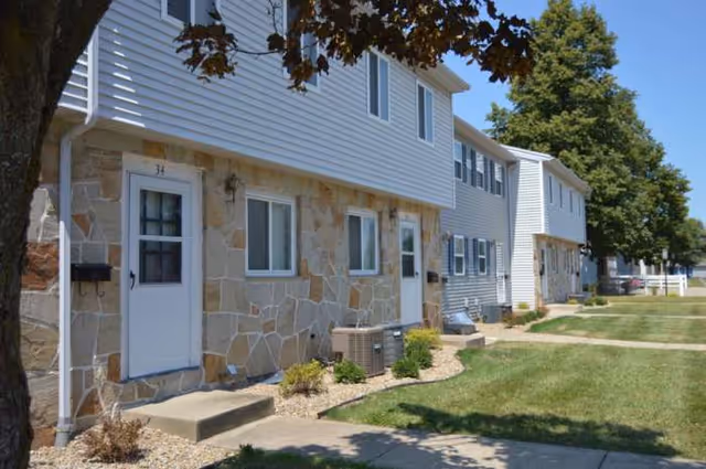 Exterior view of a multi-unit senior living building with stone and siding facade.