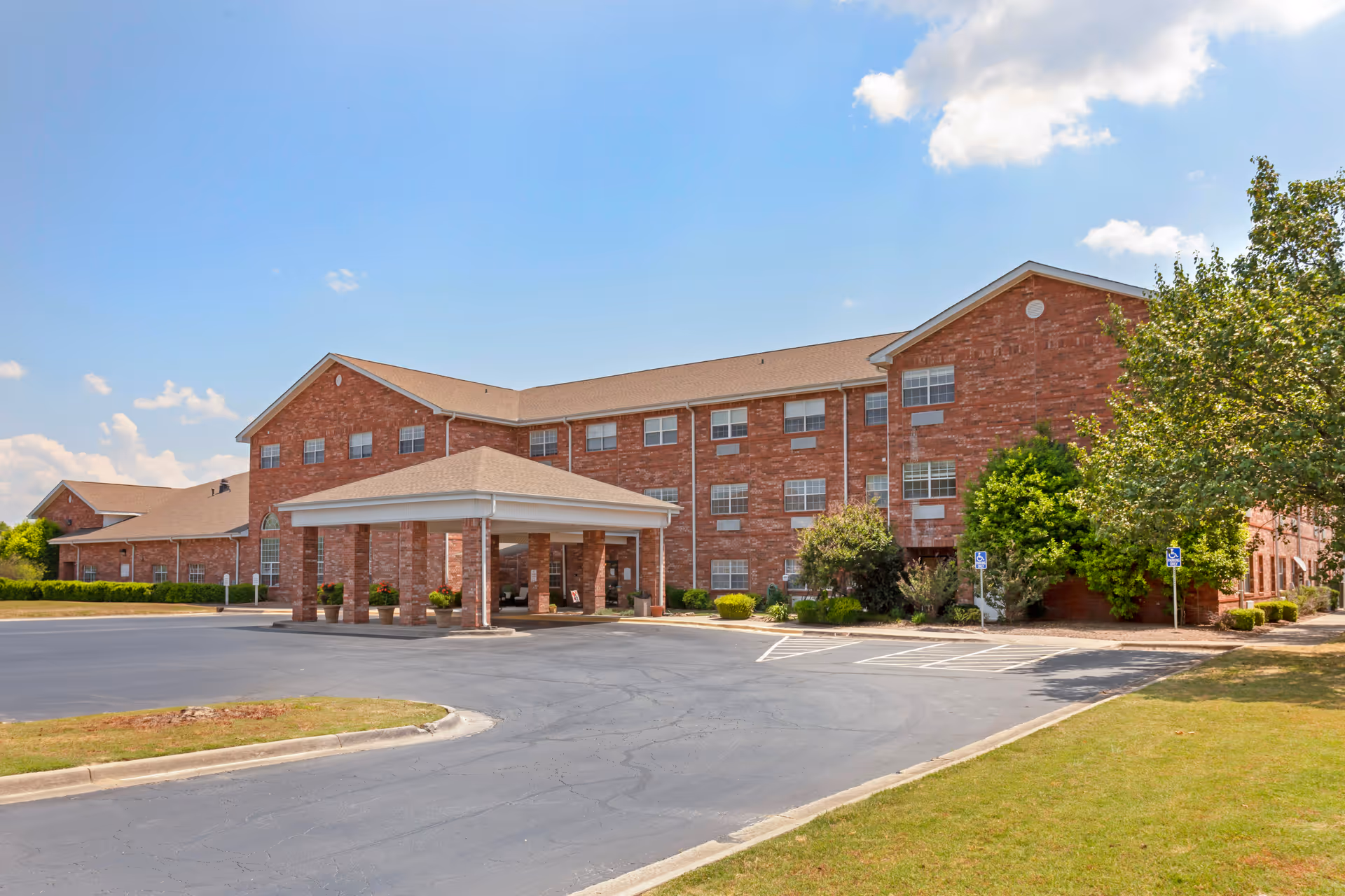 Brick senior living facility with a covered entrance and surrounding parking lot.
