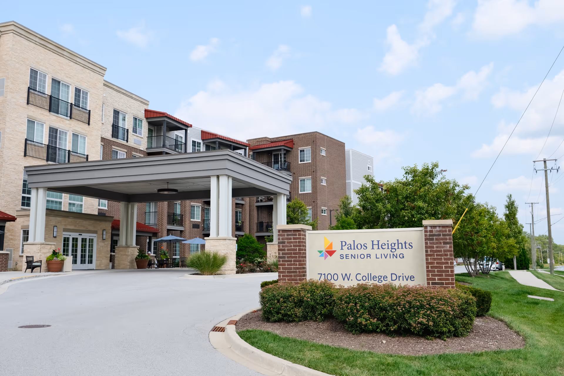 Front entrance and sign for Palos Heights Senior Living with a porte-cochère and a multi-story building in the background.