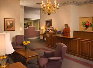 Reception lounge inside Sundale Nursing Home with a front desk, seating, and a chandelier.
