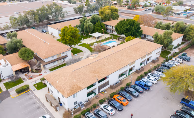Aerial view of Desert Marigold Senior Living Tempe with a long beige building, parking, and pool