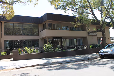 Exterior of Prospect Manor Assisted Living, a two-story beige building with large windows.