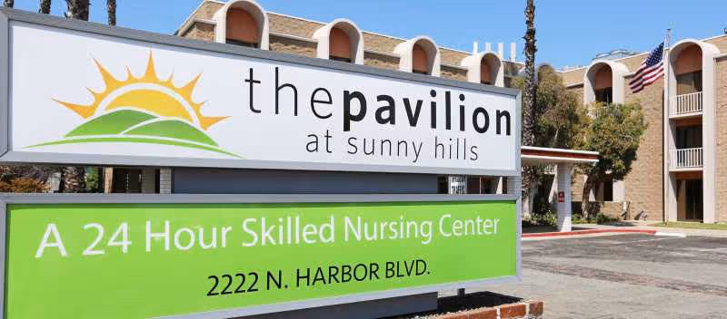 Front exterior of The Pavilion at Sunny Hills with a large sign and building in view.