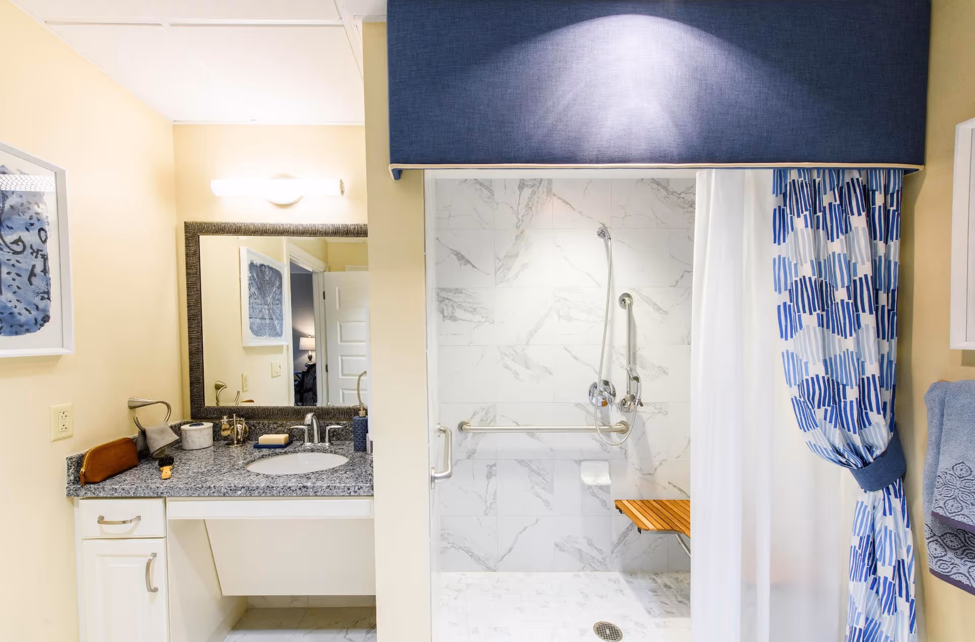 Accessible bathroom with a granite-topped sink vanity and a walk-in shower with grab bars and a patterned curtain.