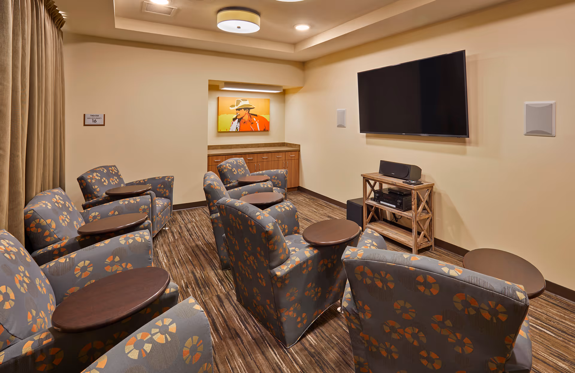 Small private theater/media room with patterned armchairs facing a wall-mounted TV and a media console.