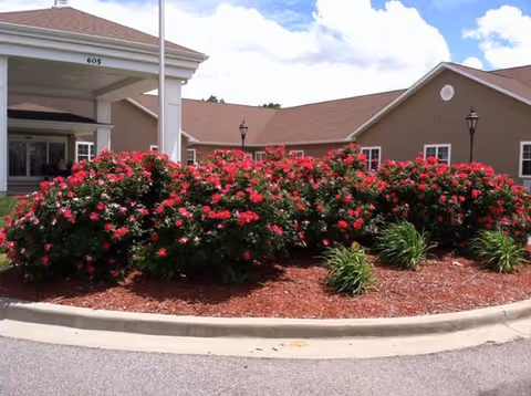 Front of Fox Meadows Supportive Living with a wraparound garden and colorful flowering bushes.