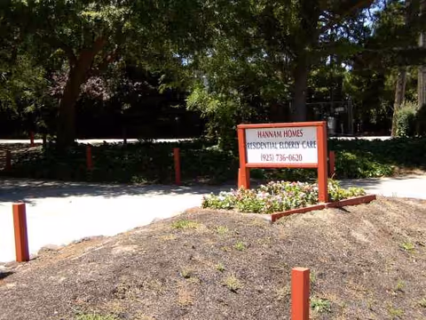 External view of Hannam Homes sign and entrance with trees and landscaping.
