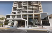 Modern multi-story senior living building with glass entrance and palm trees at the front.
