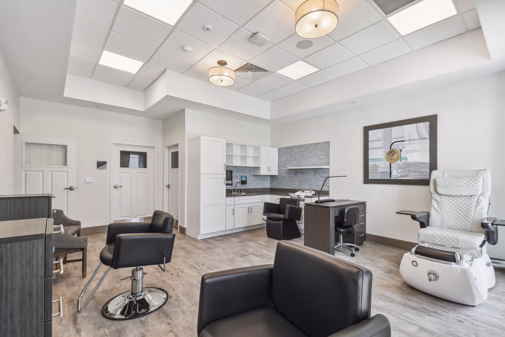 Bright salon area in a senior living facility with styling chairs, manicure/pedicure stations, cabinets and a pedicure chair.