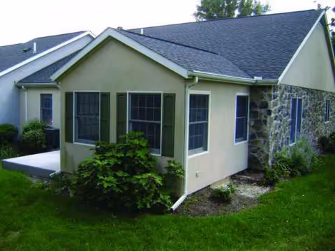 Exterior view of a beige senior living building with green lawn.