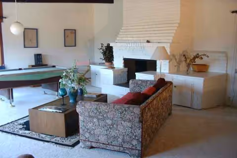 Indoor living room with a pool table, patterned sofa, coffee table, and brick fireplace.