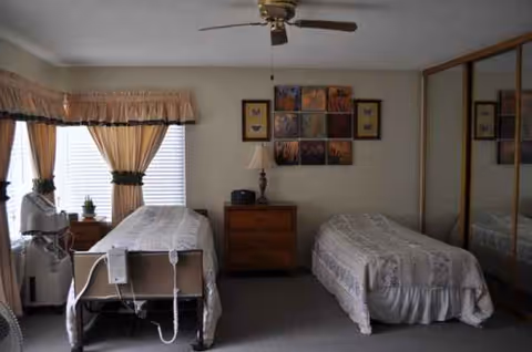 Two beds in a senior living bedroom with dresser, curtains, and mirrored closet.