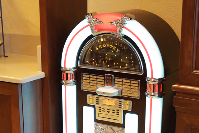 A vintage Crosley jukebox with illuminated trim standing between wooden cabinets and a countertop.
