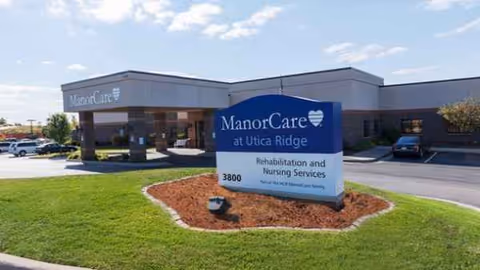 Exterior view of Harmony Utica Ridge ManorCare facility with blue sign and parking.