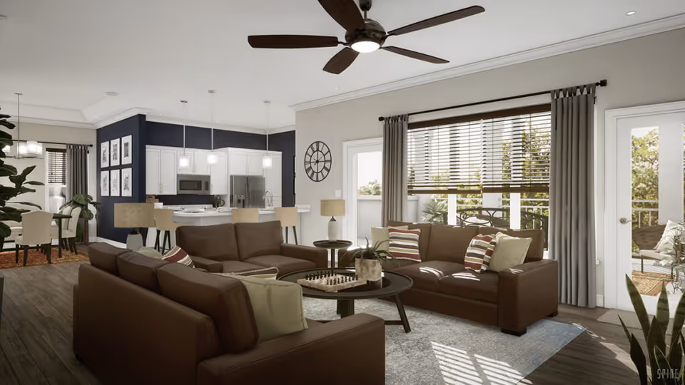 A spacious and well-lit living room with two brown leather sofas arranged around a round coffee table with a chessboard on it. The room features large windows with blinds and curtains, a ceiling fan with lights, and a door leading to an outdoor patio with seating. In the background, there is an open kitchen with white cabinets, stainless steel appliances, and a dining area with a table and chairs.