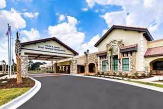 Exterior view of Clyde E. Lassen Veterans Nursing Home entrance with drive and stone facade.