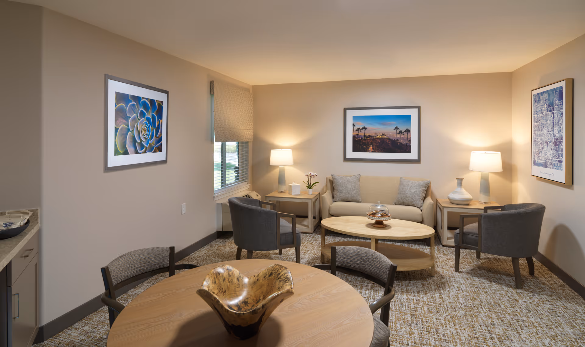 Well-lit living room with a sofa, two armchairs, a coffee table, and a round dining table with decorative bowl.