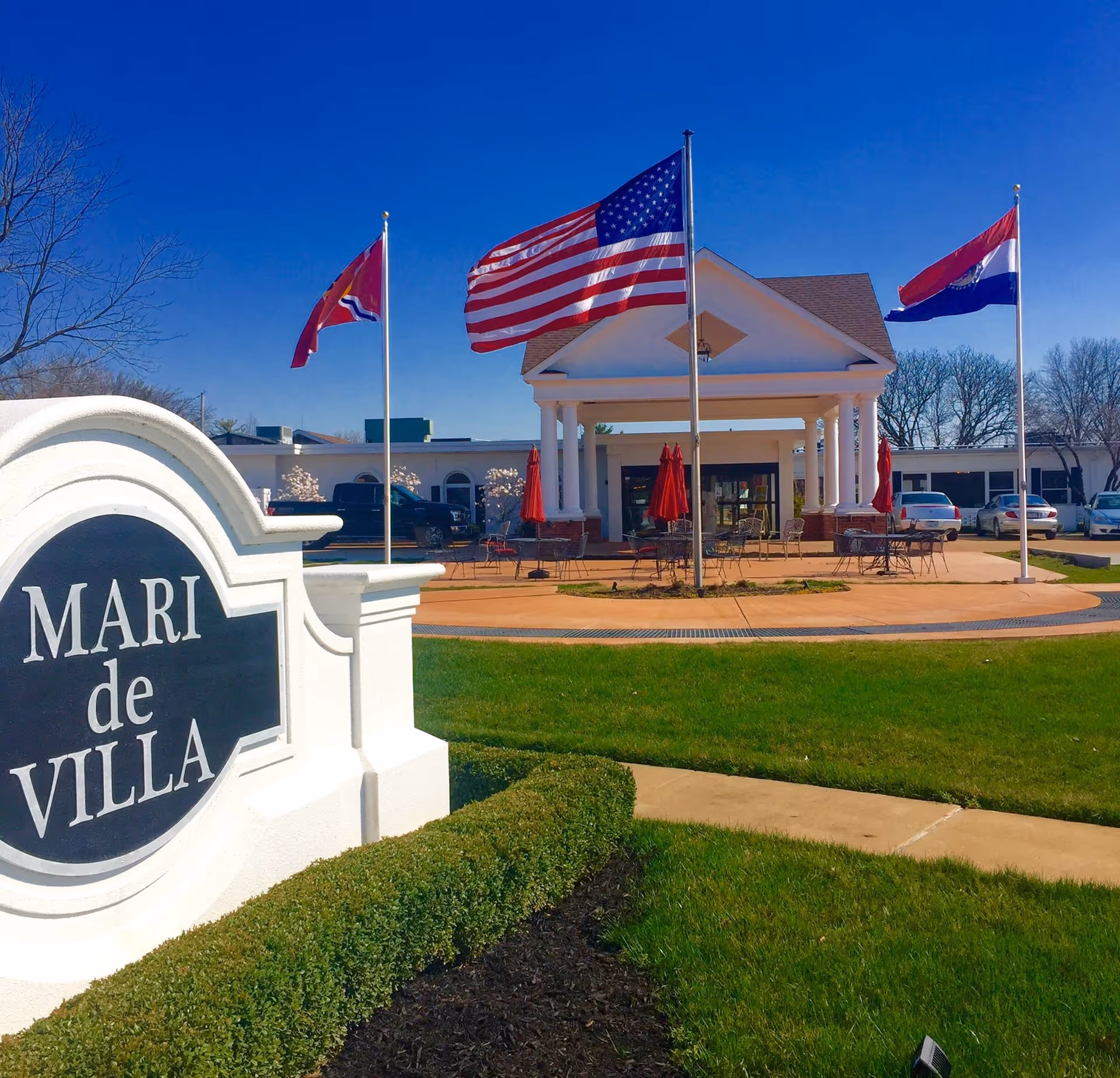 Front entrance of Mari de Villa nursing home showing the facility sign, flagpoles, and a covered portico.