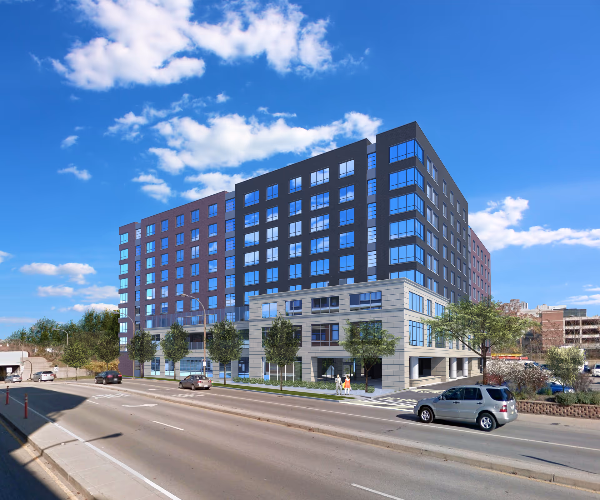 Exterior view of a multi-story senior living building with trees, parked cars, and a roadway under a blue sky.