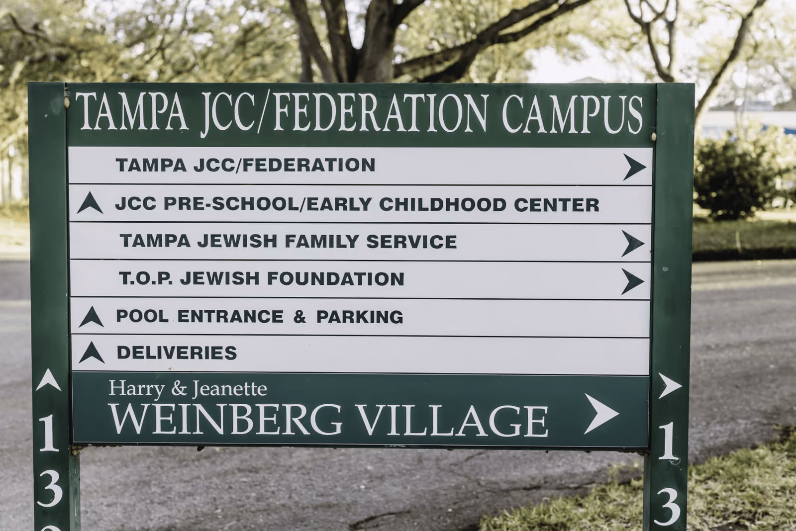 Directional sign for Tampa JCC/Federation Campus showing locations for Tampa JCC/Federation, JCC Pre-School/Early Childhood Center, Tampa Jewish Family Service, T.O.P. Jewish Foundation, Pool Entrance & Parking, Deliveries, and Harry & Jeanette Weinberg Village.