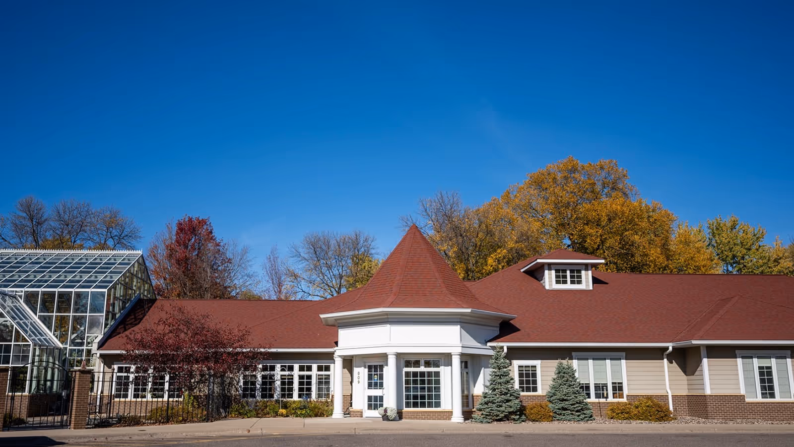 The exterior view of 'Reflections Care Suites by Three Links' featuring a prominent gabled roof and surrounding greenery.