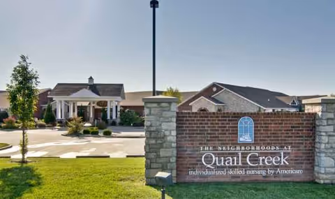 Exterior view of The Neighborhoods at Quail Creek entrance with sign and brick building.