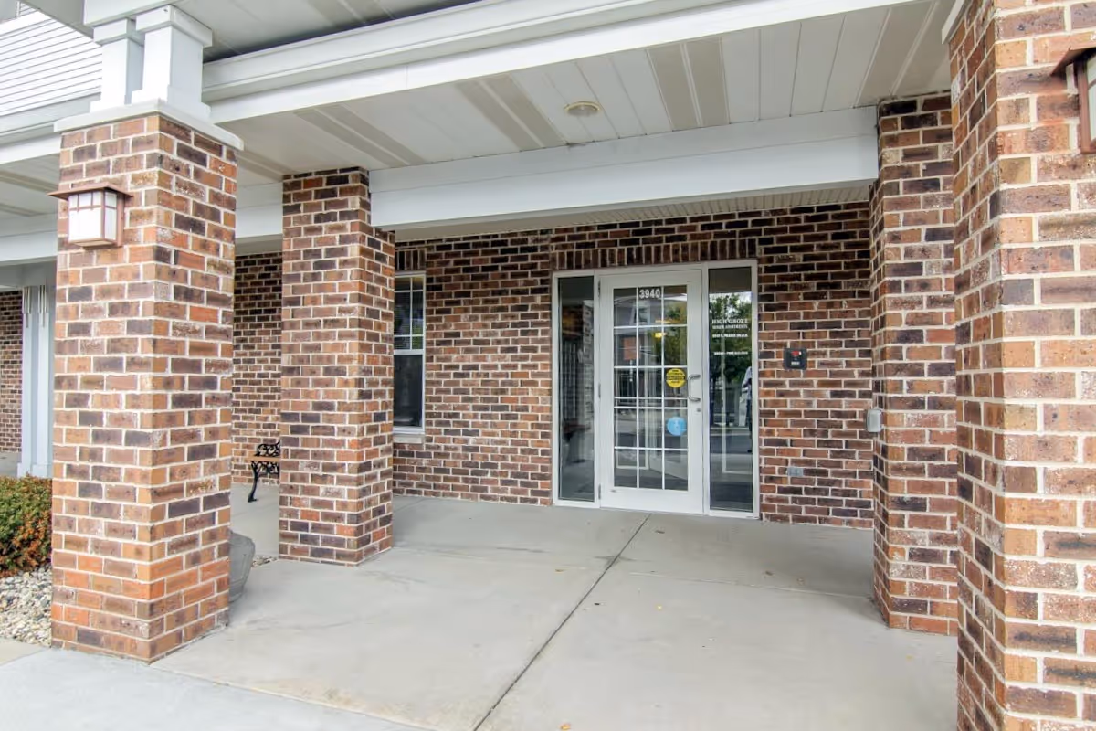Covered brick entrance with square brick columns and glass double doors.