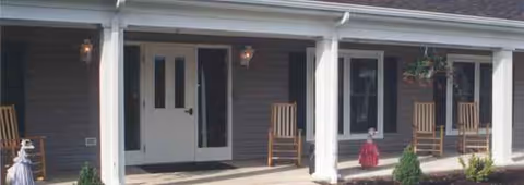 Front view of The Wyngate Senior Living Community with a covered porch and rocking chairs.