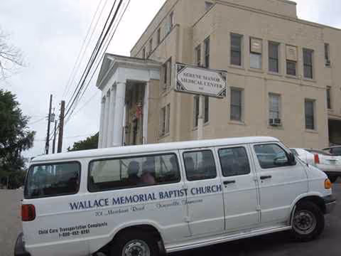 Beige multi-story building with a white van labeled Wallace Memorial Baptist Church in front.