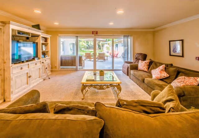 Cozy living room with brown sectional, glass coffee table, and sliding glass door to patio.