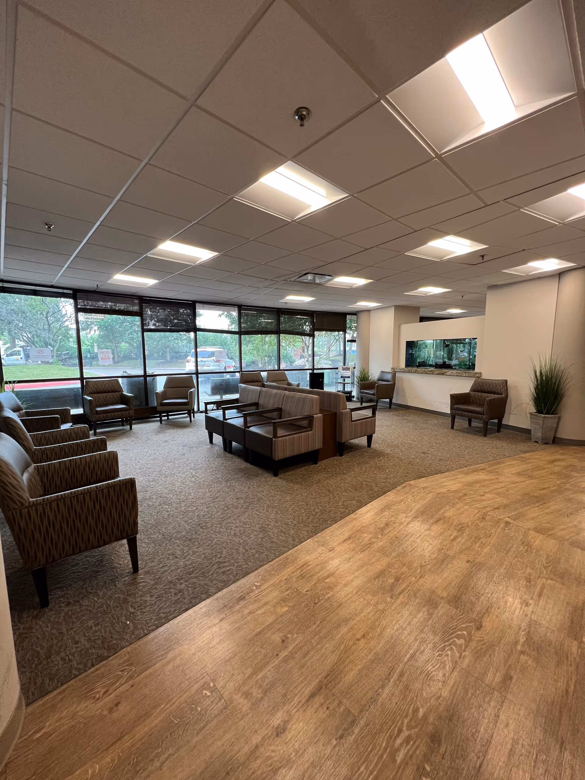 Spacious lobby/lounge with multiple armchairs and sofas, large windows, and a reception area with an aquarium.