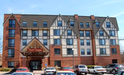 Exterior view of Maple Pointe Senior Living building with parked cars in front.