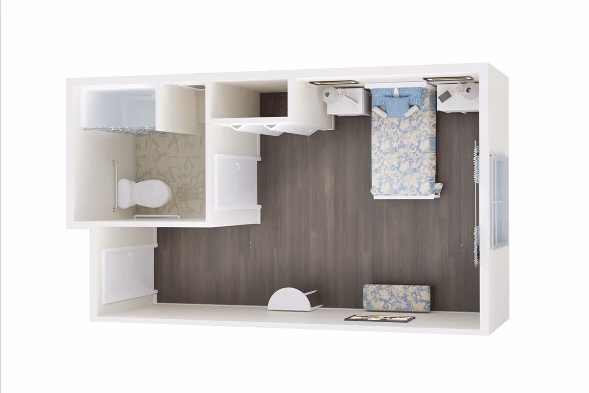 3D floor plan of a small memory care facility room featuring a bedroom area with a bed, two nightstands, a bench at the foot of the bed, and a bathroom with a toilet and shower. The room has dark wood flooring and light-colored walls.