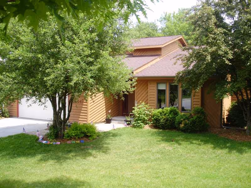 Front view of Bradford Home exterior with lawn, trees, and driveway.