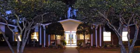 Night view of Bedford Care Center of Mendenhall front entrance with columns and trees.