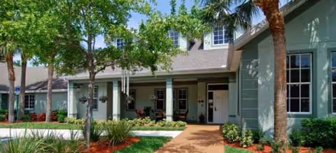 Exterior view of Brookdale Stuart building entrance with trees, shrubs, and a walkway.