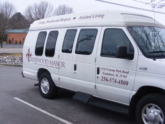 White Rosewood Manor transport van parked in lot with facility branding and contact details.