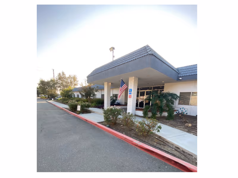 Exterior view of Gladstone Care Rehab-Glendora entrance with flag, walkway, and landscaping.