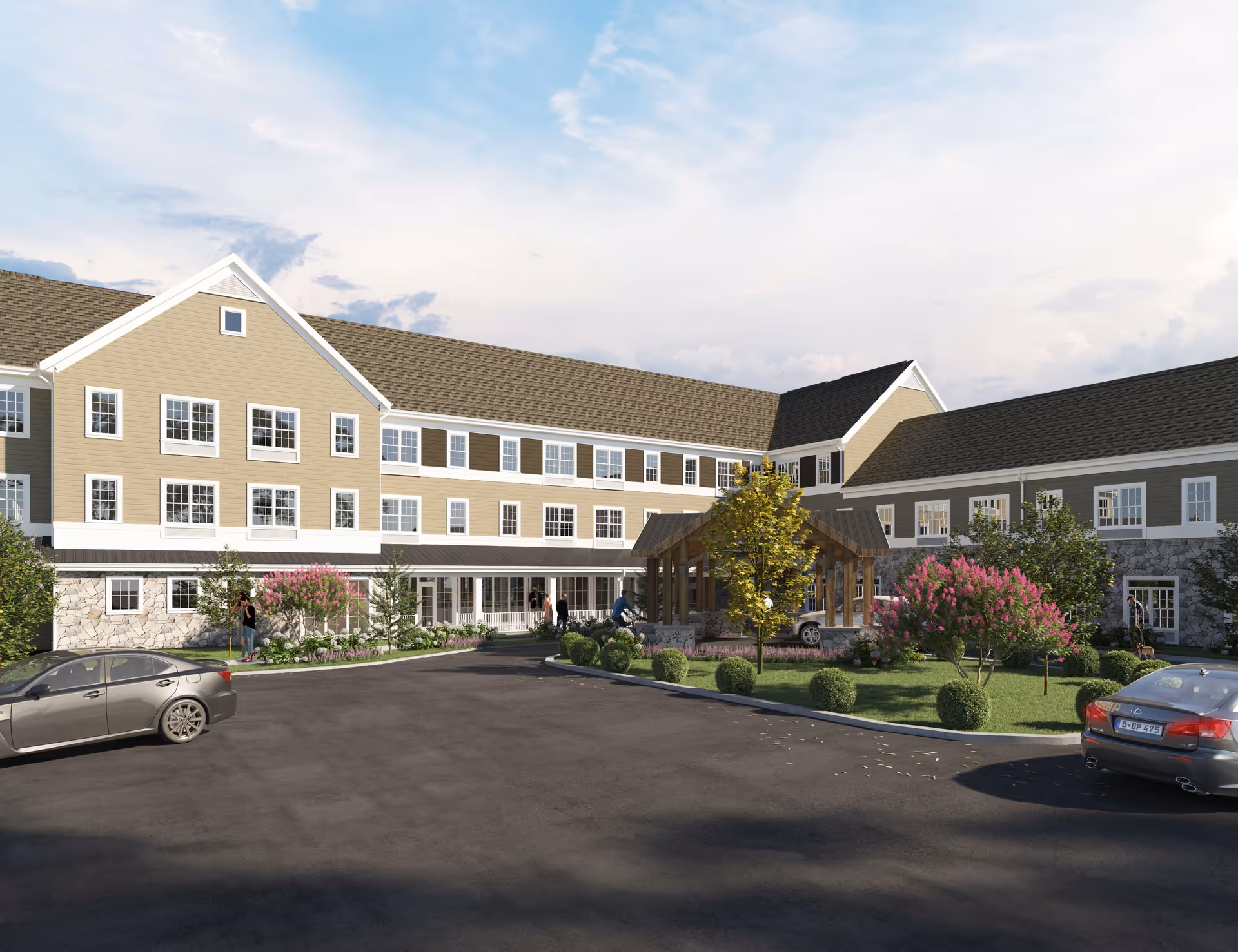 Exterior view of Ridgewood Senior Living at Historic Smithville, showing a large three-story building with beige siding, white trim, and a stone base. The building surrounds a driveway with parked cars and landscaped greenery including trees and bushes. A covered entrance is visible in the center.