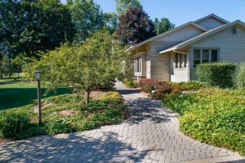 Front view of a senior living facility with a stone walkway and landscaped gardens.