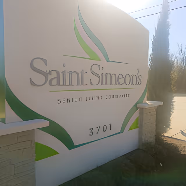 Outdoor sign for Saint Simeon's Senior Living Community with the address number 3701, featuring green and pink decorative accents on a white background.