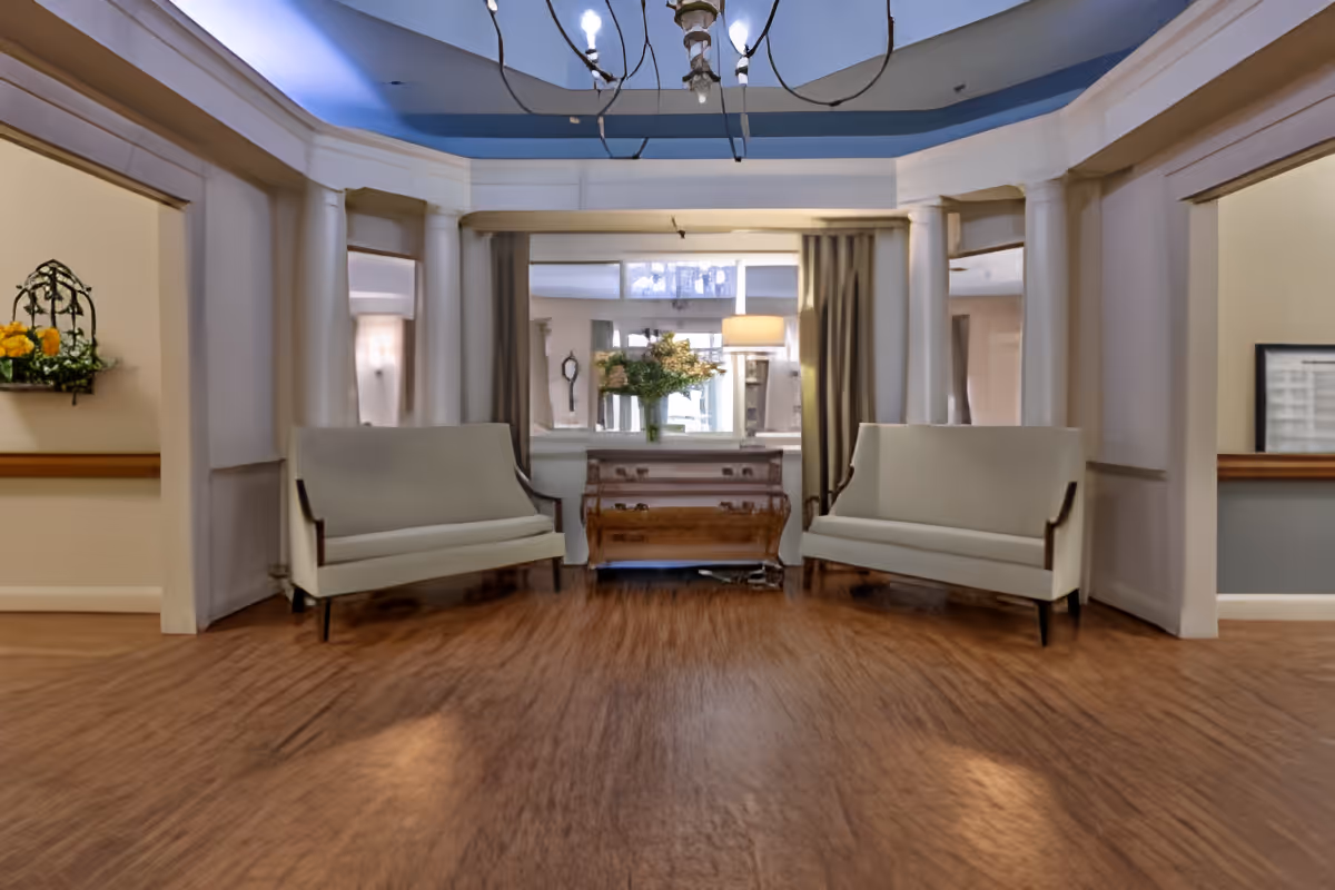Reception lobby with two upholstered benches facing a decorative chest and mirror under a domed ceiling.